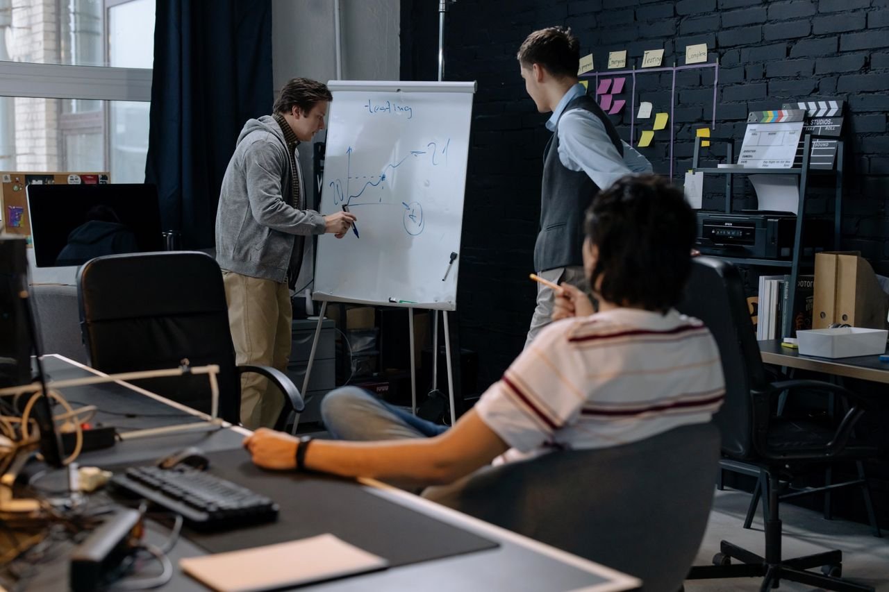 Business team in a modern office brainstorming ideas on a whiteboard. Engaged discussion and planning.