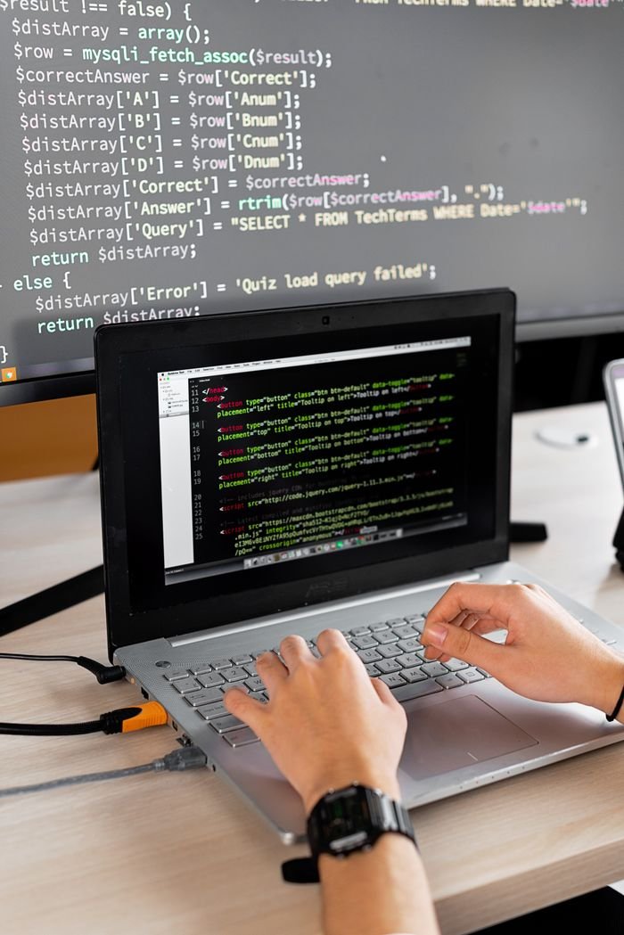 The Art of Drawing Readers In: Your attractive post title goes here Person coding at a desk with laptop and external monitor showing programming code.